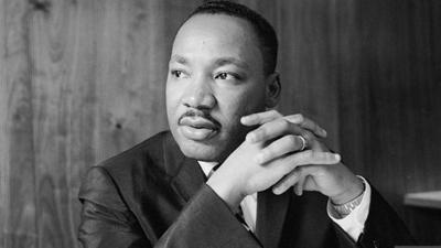A grayscale photo of MLK jr. putting his hands together