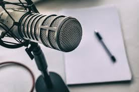 A close-up of a microphone with a pen and paper in the background