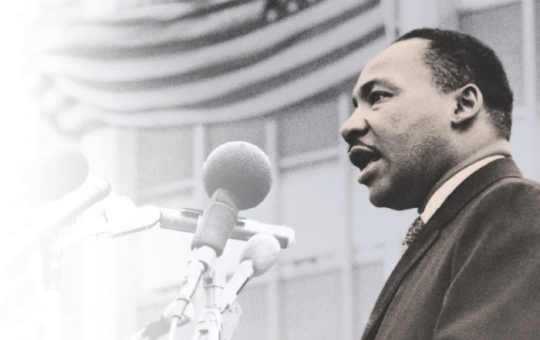 A bright photo of MLK Jr. speaking into a microphone